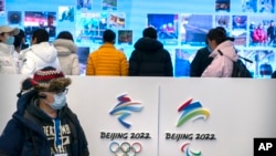 Seorang jurnalis mengenakan masker saat melihat pameran di tempat Olimpiade Musim Dingin di Yanqing di pinggiran Beijing, Jumat, 5 Februari 2021. (AP Photo/Mark Schiefelbein)