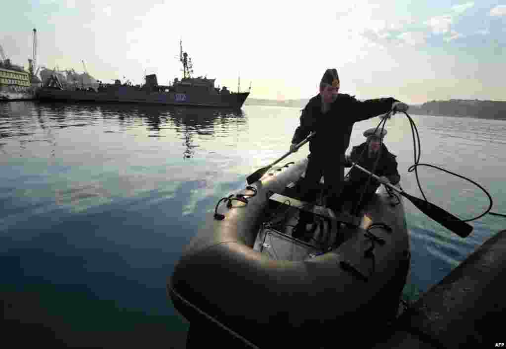 Dua tentara Angkatan Laut Ukraina tampak merapatkan perahu karetnya ke pelabuhan di Teluk Sevastopol, dekat dengan Semenanjung Krimea yang diduduki pasukan Rusia.