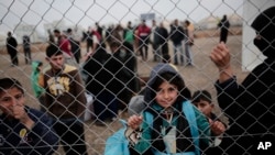 Un enfant regarde à travers le treillis dans un camp de déplacés à l’est de Mossoul, Irak, 15 février 2017.