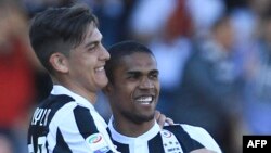 L'attaquant brésilien de la Juventus, Douglas Costa, à droite, congratule l'attaquant argentin de la Juventus Paulo Dybala après un but lors du match de football contre le Benevento Calcio au stade Ciro Vigorito, Italie, 7 avril 2018. 