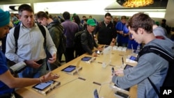 مشتریان آیفون شش در شعبه اپل در نیویورک ویژگی های گوشی جدید را بررسی می کنند.