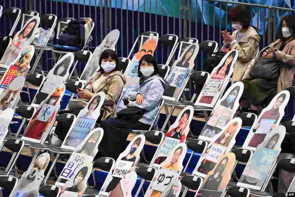 Spectators sit among the figures with pictures of the fans and animals ahead of the ISU World Team Trophy figure skating event in Osaka, Japan.