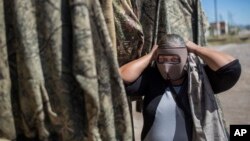 FILE - A vendor shows a mask used by migrants as protection from the low desert night temperatures they face during their treks to the United States, in Sonoyta, in the northern Mexican state of Sonora, April 4, 2017. 