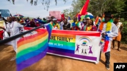 FILE - People holding rainbow flags take part in the Gay Pride parade in Entebbe, Aug. 8, 2015. 