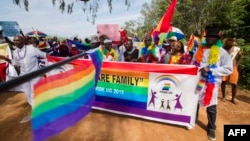 FILE - People holding rainbow flags take part in the Gay Pride parade in Entebbe, Uganda, Aug. 8, 2015. 