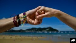 Una pareja se toma de las manos frente a la playa La Concha en la ciudad vasca de San Sebastián, en el norte de España, el domingo 10 de junio de 2018. Miles de manifestantes formaron una cadena humana durante media hora en las ciudades vascas de Vitoria, Bilbao y San Sebastián el domingo para exigir un voto de independencia.
