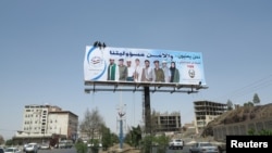 Workers put up a billboard urging citizens to cooperate with security authorities in Sana'a, Yemen, September 30, 2013, the day of the suspected al-Qaida attack on an army base in the eastern city of al-Mukalla.