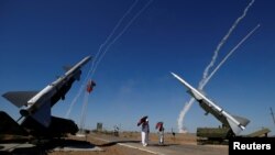 FILE - People watch S-300 air defense missile systems launching missiles during the International Army Games 2017 at the Ashuluk shooting range outside Astrakhan, Russia, Aug. 5, 2017. 