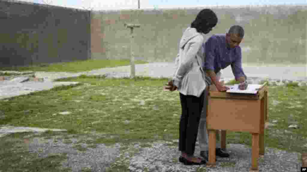 President Obama and Michelle Obama sign a guest book during a tour of Robben Island.