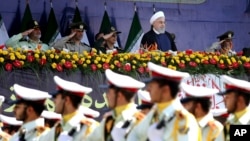 Iran's President Hassan Rouhani, top center, reviews army troops marching during the 38th anniversary of Iraq's 1980 invasion of Iran, in front of the shrine of the late revolutionary founder, Ayatollah Khomeini, outside Tehran, Iran, Sept. 22, 2018.