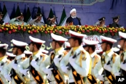 Iran's President Hassan Rouhani, top center, reviews army troops marching during the 38th anniversary of Iraq's 1980 invasion of Iran, in front of the shrine of the late revolutionary founder, Ayatollah Khomeini, outside Tehran, Iran, Sept. 22, 2018.