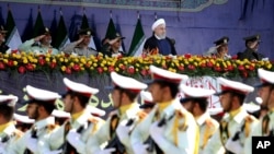 FILE - Iran's President Hassan Rouhani, top center, reviews army troops.
