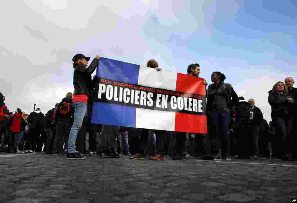 Polisi memegang bendera Perancis bertuliskan &quot;Polisi yang Marah&quot; dalam demonstrasi di depan Majelis Nasional di Paris (26/10). (AP/Christophe Ena)