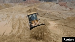 A labourer operates a bulldozer at a site of a rare earth metals mine at Nancheng county, Jiangxi province,China.
