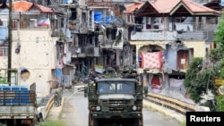Soldiers on a military truck drive past houses and buildings damaged after government troops cleared the area from pro-Islamic State militant groups inside the war-torn Marawi city, southern Philippines, Oct. 19, 2017. 