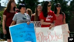 FILE - Sonja Breda, 23, right, holds a sign saying "Stop Betsy" as a group of survivors of sexual violence and their supporters gather to protest proposed changes to Title IX before a speech by Education Secretary Betsy DeVos, Thursday, Sept. 7, 2017, at the George Mason University Arlington, Va., campus. (AP Photo/Jacquelyn Martin)