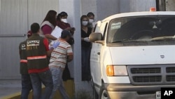 Forensic workers prepare to transfer bodies from a van into a large truck, not seen, in the northern border city of Matamoros, Mexico, April, 6, 2011