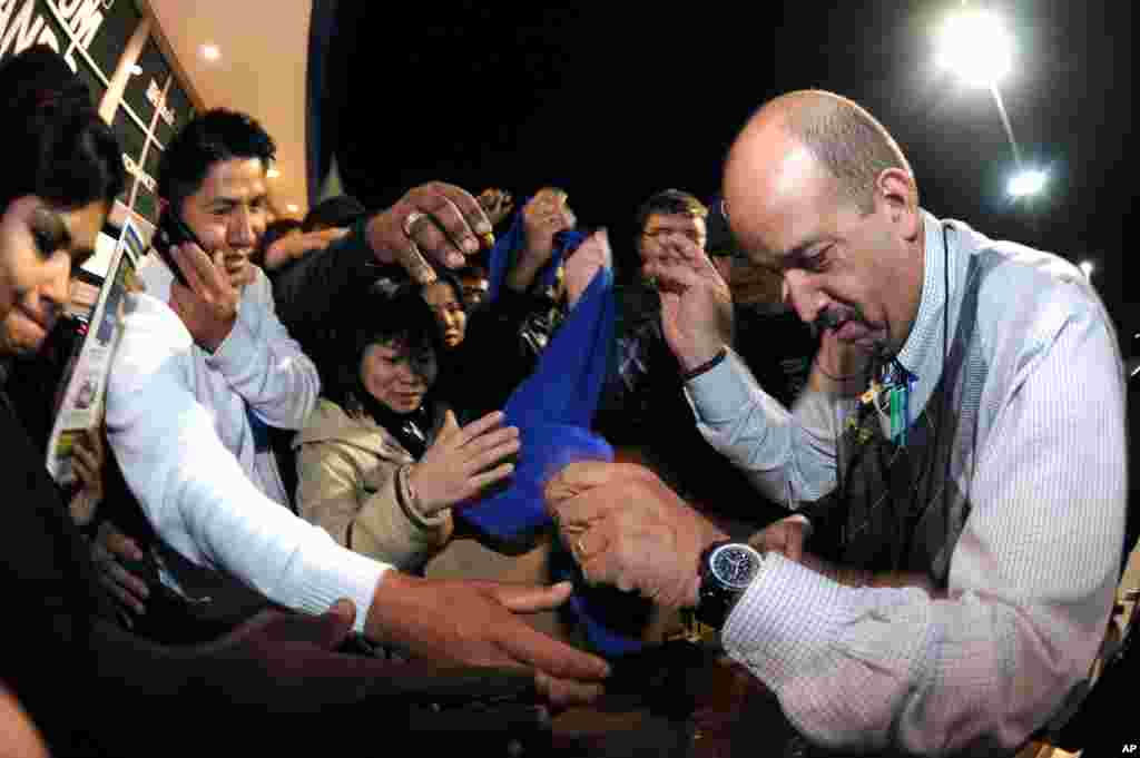 Best Buy bargain hunters swarm manager Ramon Estevez as he hands out scarves and hats that will identify those eligible for specially priced door-buster sale items late in the evening on Thanksgiving Day in Dunwoody, Georgia, Nov. 28, 2013.