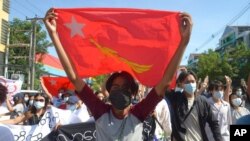 FILE - Anti-coup protesters display a party flag of the National League for Democracy (NLD) during a demonstration in Yangon, Myanmar, May 14, 2021. 