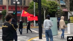 上海靜安區居民排隊做新冠病毒核酸檢測，路上有人打著中共與中國的旗幟走過。 （2022年4月1日）