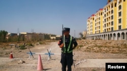 FILE - A Chinese police officer takes his position by the road near what is officially called a vocational education center in Yining in Xinjiang Uighur Autonomous Region, China, Sept. 4, 2018. 