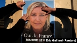 In this 2014 file photo, supporters paste a poster of Marine Le Pen, France's National Front leader, on a wall before a political rally in 2014. (REUTERS/Eric Gaillard )