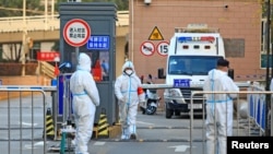 Workers in protective suits stand at an entrance to a university's residential area under lockdown following the coronavirus disease (COVID-19) outbreak in Xian, Shaanxi province, China, Dec. 20, 2021. (China Daily via Reuters)