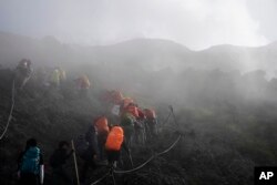 Orang-orang mendaki menembus kabut tebal saat menyusuri jalur Yoshida menuju puncak Gunung Fuji, Senin, 26 Agustus 2019, di Jepang. (Foto: AP)