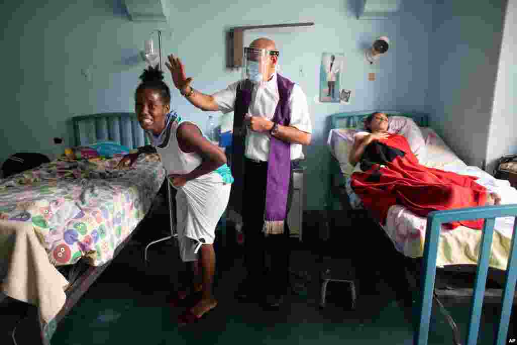 Father Felix Mendoza, a Catholic priest, center, prays over a woman who cries, saying she is in physical pain, at a public hospital in Caracas, Venezuela, May 11, 2021, amid the COVID-19 pandemic.