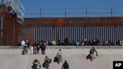 Rombongan migran tampak menedekati dinding perbatasan di Ciudad Juarex, Meksiko, yang membatasi wilayah Meksiko dengan El Paso, Texas, pada 21 Desember 2022. (Foto: AP/Christian Chavez)