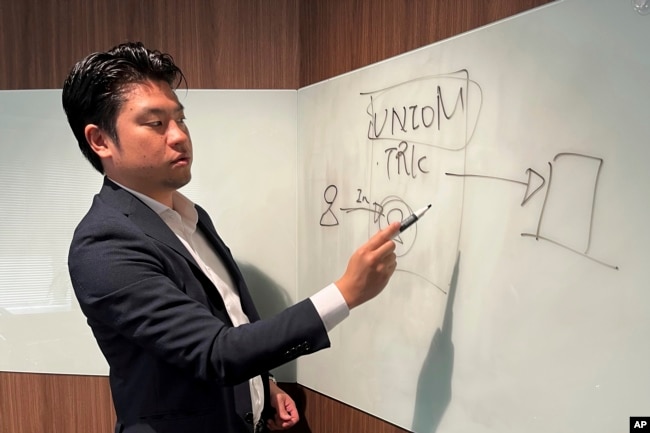 Yoshihito Hasegawa, who heads Tokyo-based TRK that runs a job-quitting service called Guardian, shows a diagram to explain what his service does at his office in Tokyo on June 21, 2023. (AP Photo/Yuri Kageyama)