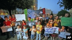 Zarokên Sûrî û malbatên wa wêneyn Hamza El Katîb ê 13 salî bilind dikin û muman veidixin. Avahîya Neteweyên Yekbûyî, Beyrut, Hezîran 1, 2011