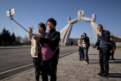 FILE - Tourists from China pose for photos before the Three Charters monument in Pyongyang, April 15, 2019. North Korea will ban foreign tourists to protect itself against a new SARS-like virus that has claimed at least 17 lives in China.