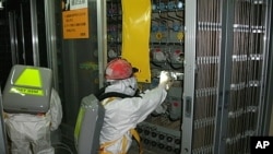 Workers wearing protective suits check the status of the water level indicator at the fuel area inside the crippled Fukushima Daiichi Nuclear Power Plant Number 1 reactor in Fukushima Prefecture May 10, 2011.