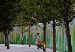 A woman wearing a protective mask, amid the coronavirus disease (COVID-19) outbreak, pushes a stroller outside the National Stadium, the main venue of the Tokyo 2020 Olympic Games in Tokyo, Japan, July 28, 2021.