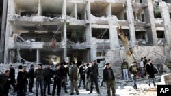 Syrian security officers gather in front the damaged building of the aviation intelligence department, which was attacked by one of two explosions in Damascus, Syria, in March. An al-Qaida-style group claimed that it carried out the double suicide bombing.