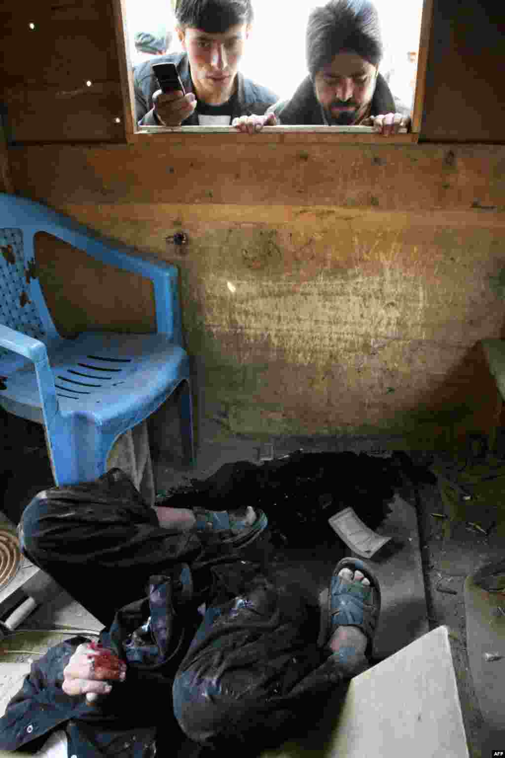 Afghans look at the body of a militant who was shot at a security booth in Kabul, April 16, 2012. (AP)