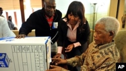 Former president Nelson Mandela, assisted by his grand daughter Ndileka Mandela and an IEC official, casts his special vote for the local government elections at his home in Houghton, Johannesburg, May 16, 2011