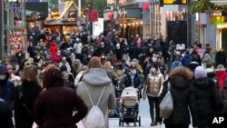 FILE - People wear mandatory face masks in a shopping street in Dortmund, Germany, Dec. 1, 2021. Germany has tightened the COVID-19 rules because of the pandemic.