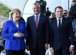 FILE - German Chancellor Angela Merkel, left, and French President Emmanuel Macron welcome Kosovo's President Hashim Thaci, center, to the Chancellery in Berlin, Germany, April 29, 2019.