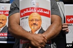 FILE - Friends of slain Saudi journalist Jamal Khashoggi hold posters bearing his picture as they attend an event marking the second-year anniversary of his assassination in front of Saudi Arabia Istanbul Consulate, on Oct. 2, 2020.