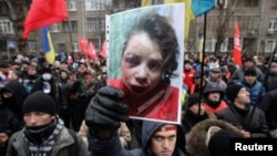 A protester holds a picture of journalist Tetyana Chornovil, who was beaten and left in a ditch just hours after publishing an article on the assets of top government officials, during a protest rally in front of the Ukrainian Ministry of Internal Affairs Internal Affairs in Kyiv, Dec. 25, 2013.