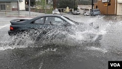 Un auto intenta circular entre las calles inundadas en Los Ángeles, mientras continúan las lluvias en California.