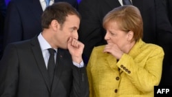 FILE - French President Emmanuel Macron, left, and German Chancellor Angela Merkel chat during a group photo at an EU summit at the Europa building in Brussels, Belgium, Dec. 14, 2017.