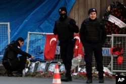 A police officer looks at the photographs of the victims as two others stand guard a day after an attack at a popular nightclub in Istanbul, Jan. 2, 2017.