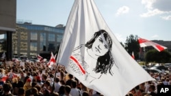 People hold a flag with a portrait of Sviatlana Tsikhanouskaya, former candidate for the presidential elections, during a rally in Minsk, Belarus, Monday, Aug. 17, 2020. Workers heckled and jeered President Alexander Lukashenko on Monday as he…
