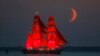 A brig with scarlet sails travels on the Finnish Gulf coast during a rehearsal for the Scarlet Sails festivities marking school graduation which will take place on June 27 in St. Petersburg, Russia, with the setting moon in the background. 