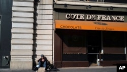 FILE - A homeless man sits in front to a closed shop near Rivoli street in Paris, France, April 21, 2020, during a nationwide lockdown to counter the coronavirus pandemic.
