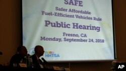 FILE - Mike Stoker, regional administrator of US EPA and Jonathan Morrison of NHTSA listen to speakers during the first of three public hearings on the Trump administration's proposal to roll back car-mileage standards in a region with some of the worst air pollution.