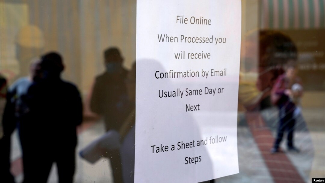 People who lost their jobs are reflected in the door of an Arkansas Workforce Center as they wait in line to file for unemployment following an outbreak of the coronavirus disease (COVID-19), in Fort Smith, Arkansas.